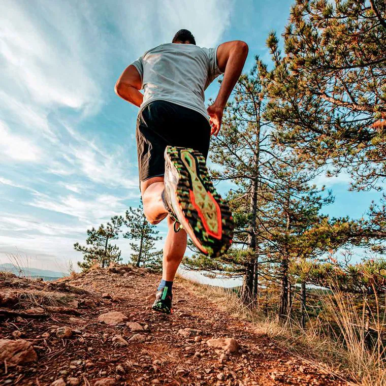 Un corridore su un sentiero sterrato di montagna, in abbigliamento tecnico