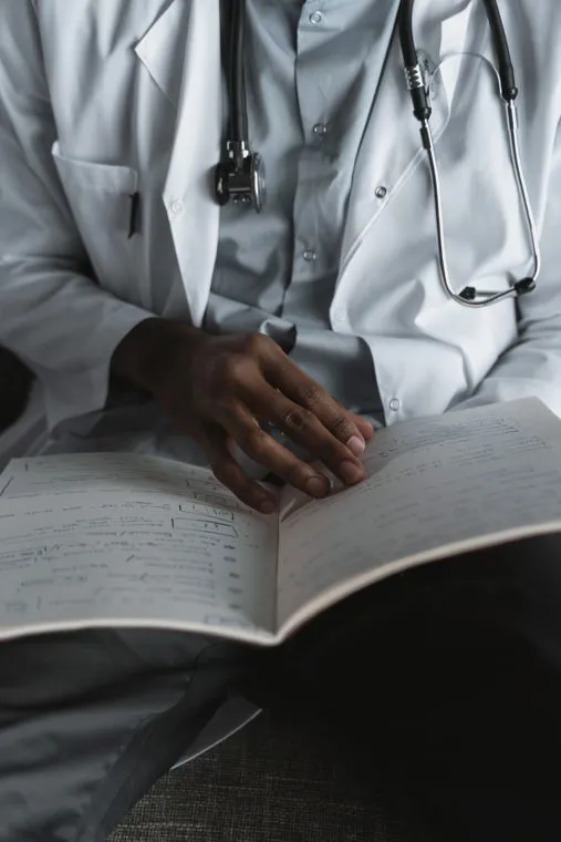Un medico in camice, con lo stetoscopio al collo, che consulta un registro