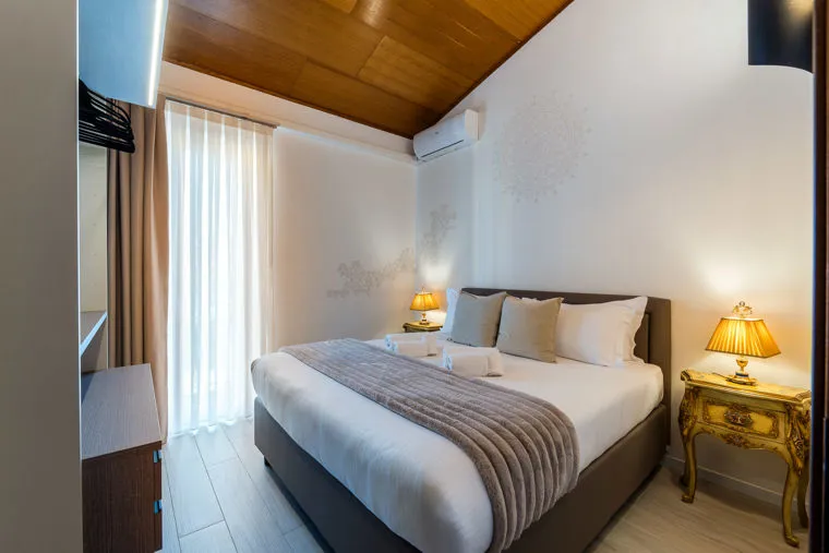 Una camera dell'albergo con il letto matrimoniale e il soffitto in travi di legno